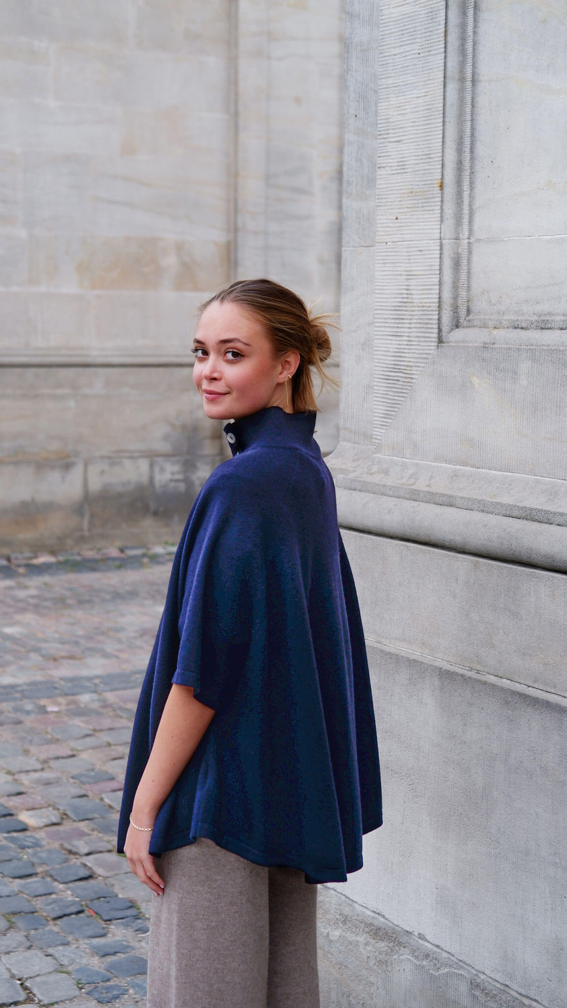 Model iført den marineblå cashmere poncho med knapper set bagfra.