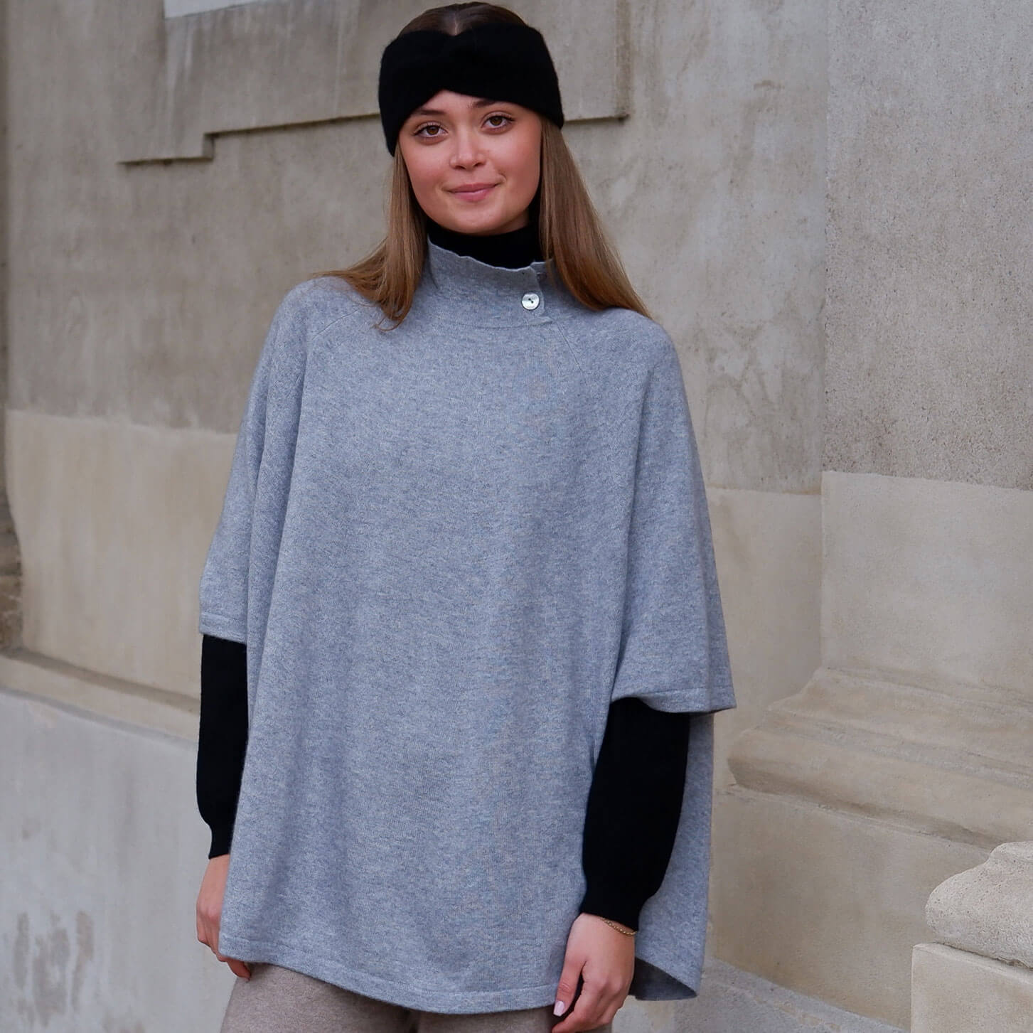 Model iført lysegrå cashmere poncho med knapper. 