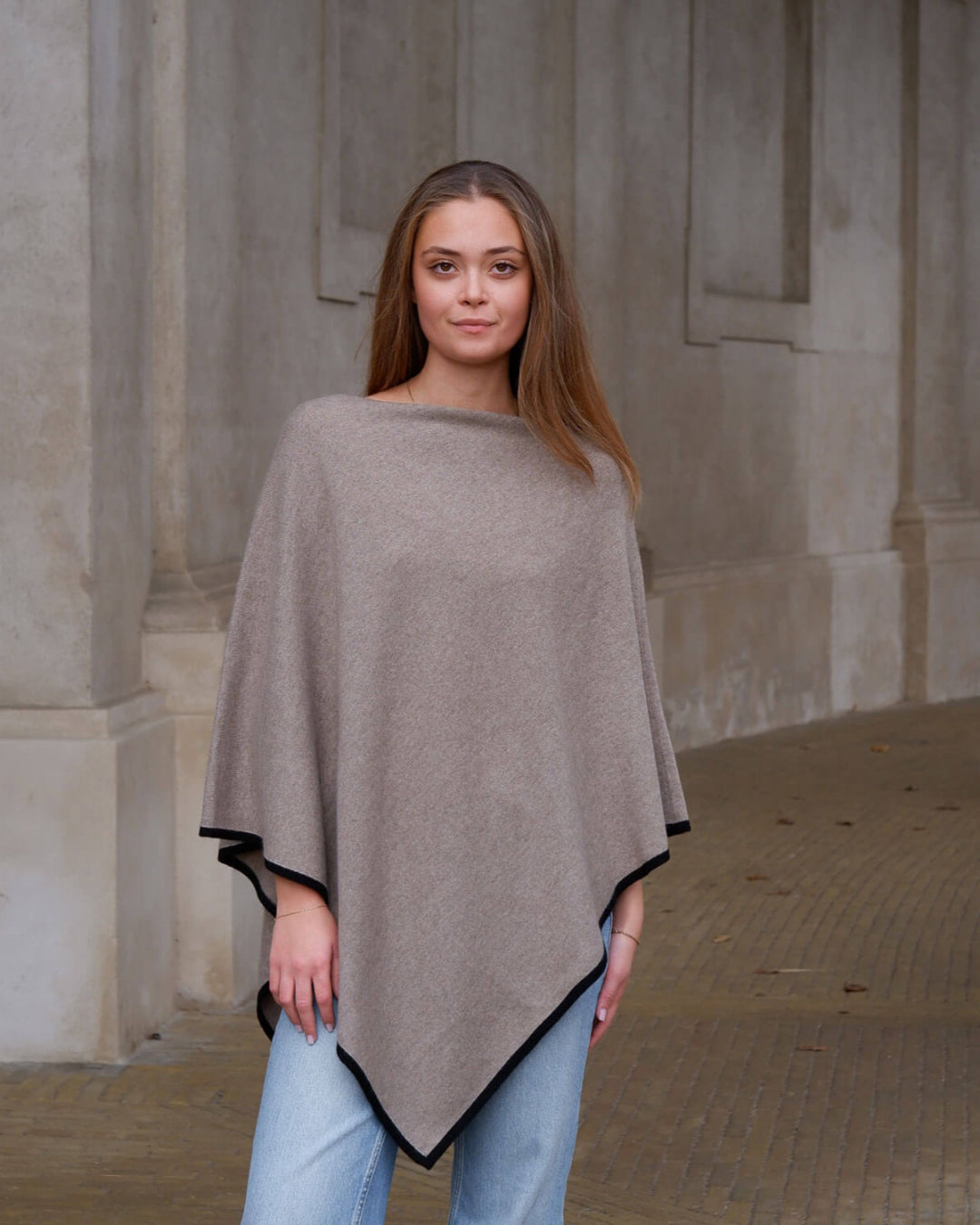 Model iført elegant mørkbeige cashmere poncho med sort stribe.
