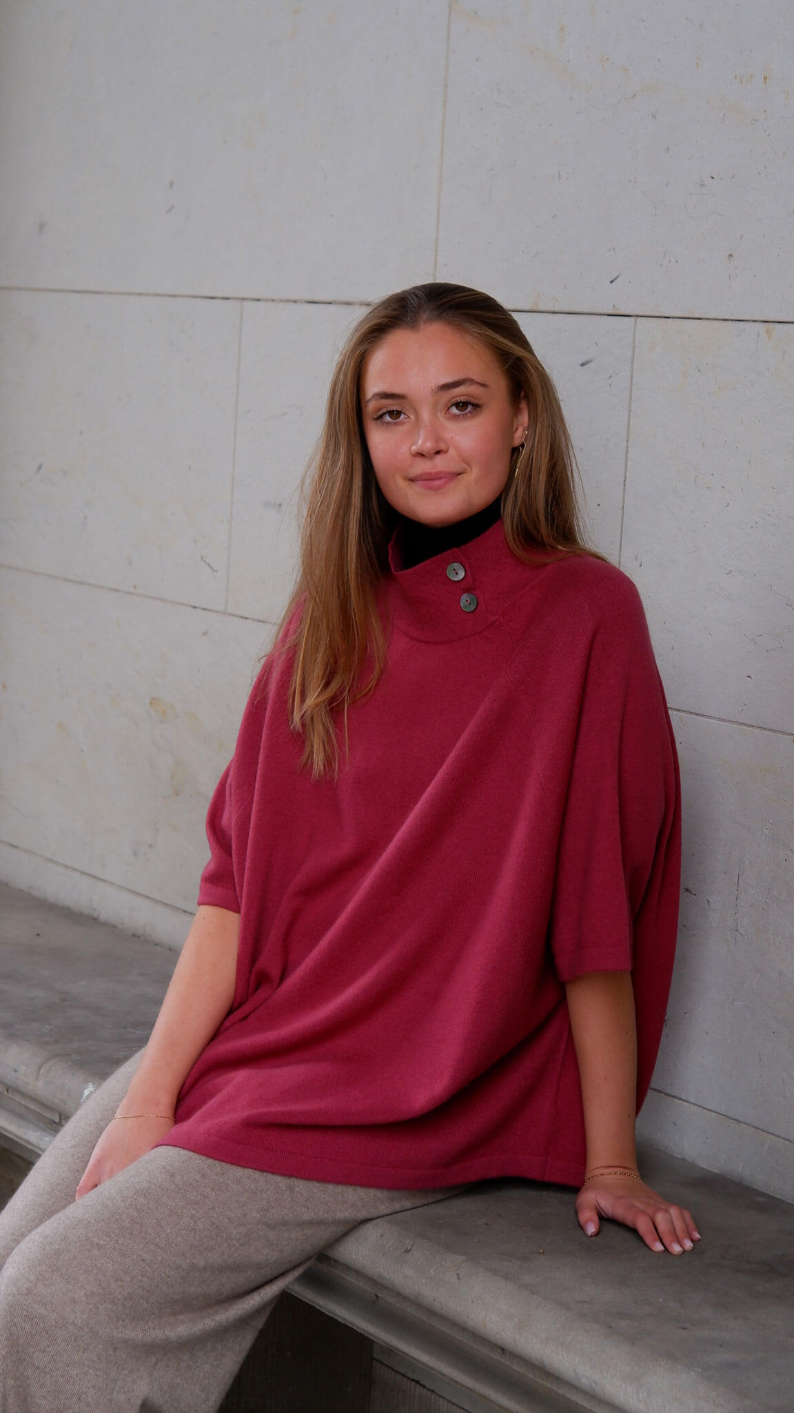 Model iført bordeaux cashmere poncho med knapper smukt draperet.