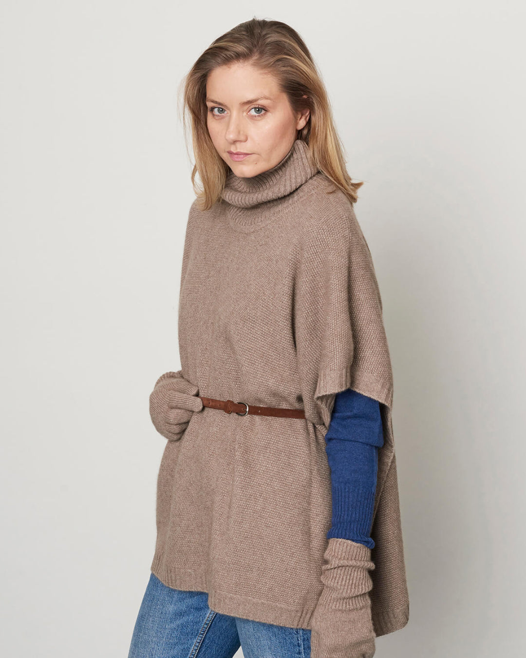 Model iført cashmere poncho med rullekrave, stylet med bælte.