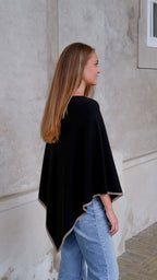 Model iført sort cashmere poncho med mørkbeige kant.