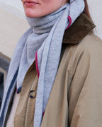 Lys gråt cashmere tørklæde med kantdetaljer, der fremhæver dets feminine og elegante design.