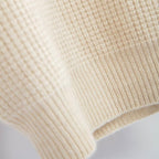 Closeup af cashmere lys beige turtleneck, der viser den fine ternede struktur i strikken.