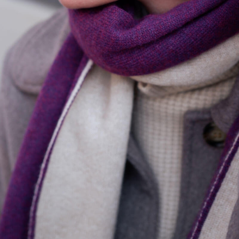 Nærbillede af det to-farvede halstørklæde i cashmere, der fremhæver farverne grape purple og lys beige.