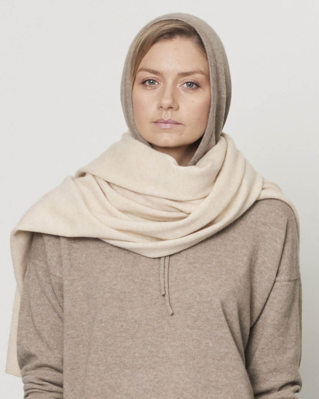 Model med det store naturfarvede cashmere tørklæde i lys beige svøbt om halsen.