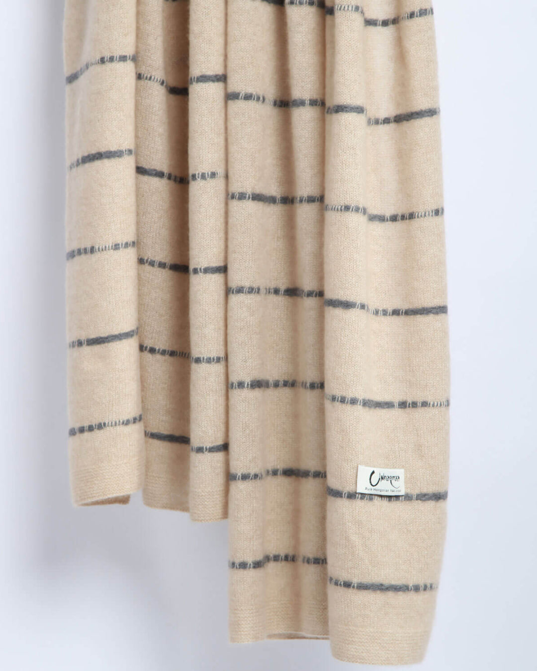 Detaljevisning af det stribede mønster på det lys beige cashmere tørklæde.