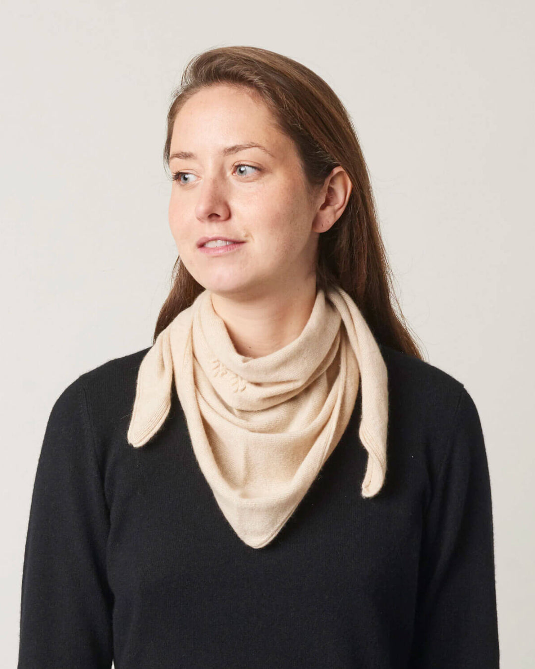 Kvinde iført et lille trekantet cashmere tørklæde i lys beige