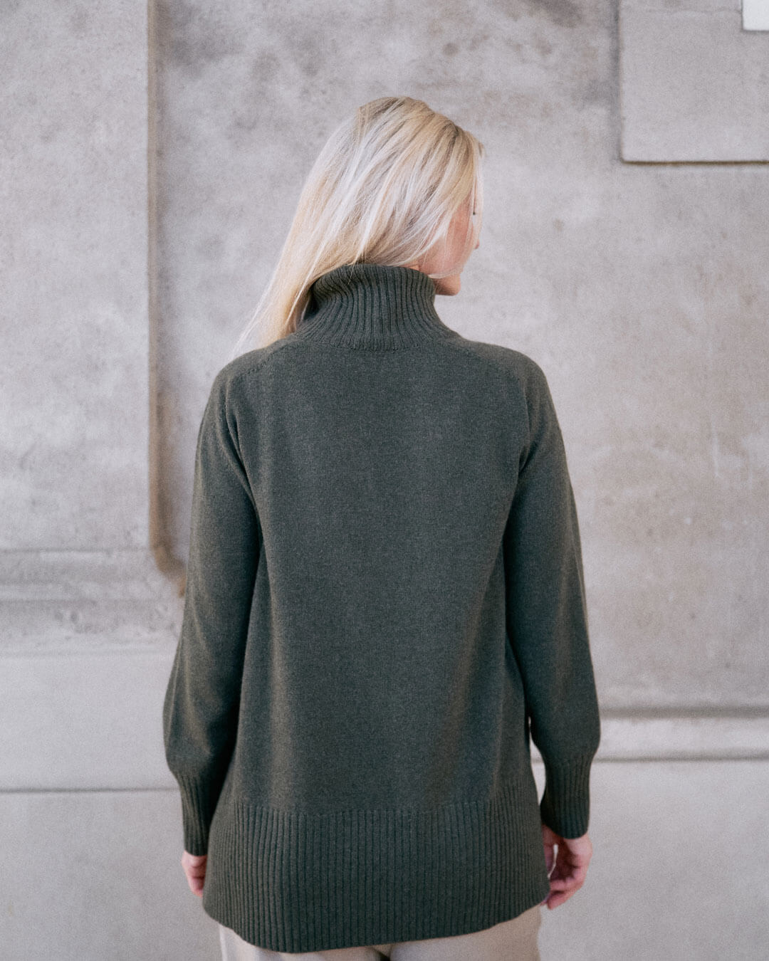 Model iført klassisk cashmere sweater med sadelskuldre og løs pasform i army green set bagfra