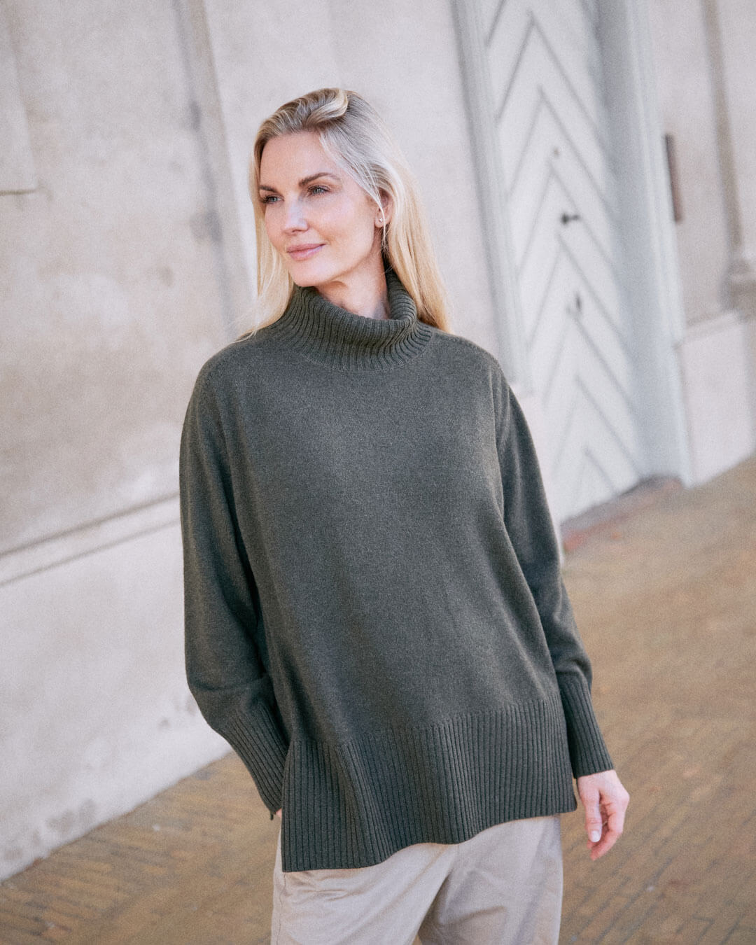 Model iført klassisk cashmere sweater med sadelskuldre og løs pasform i army green i afslappet pose