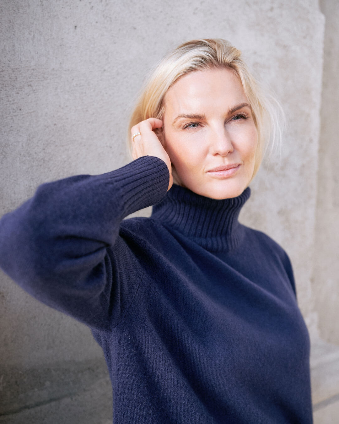 Close up af model iført klassisk cashmere sweater med sadelskuldre og løs pasform i dark navy