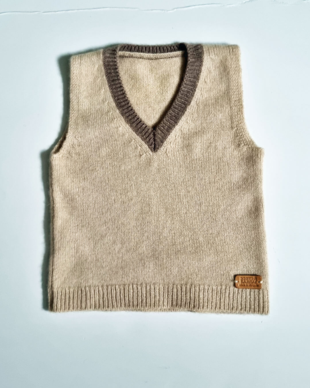 Klassisk V-hals med kontrastkant i naturlige farver.