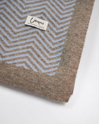 Detalje af plaid i ice blue cashmere og platinum grey yakuld med Undarmaa-logo, i sildemønstret design.