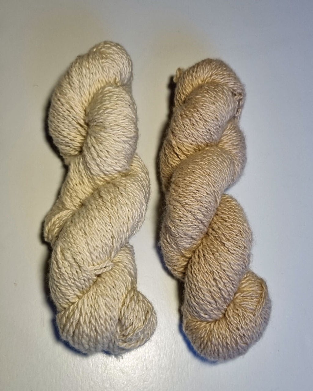 To nøgler håndspundet cashmeregarn i farverne natural white og natural sand.