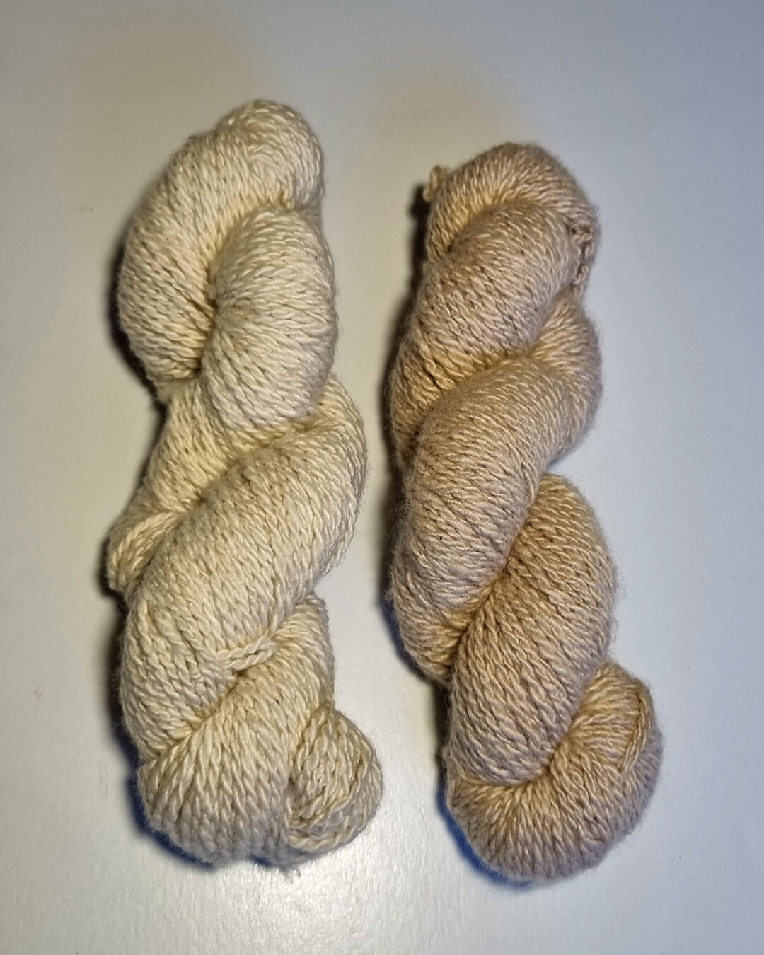 To nøgler håndspundet cashmeregarn i farverne natural white og natural sand.