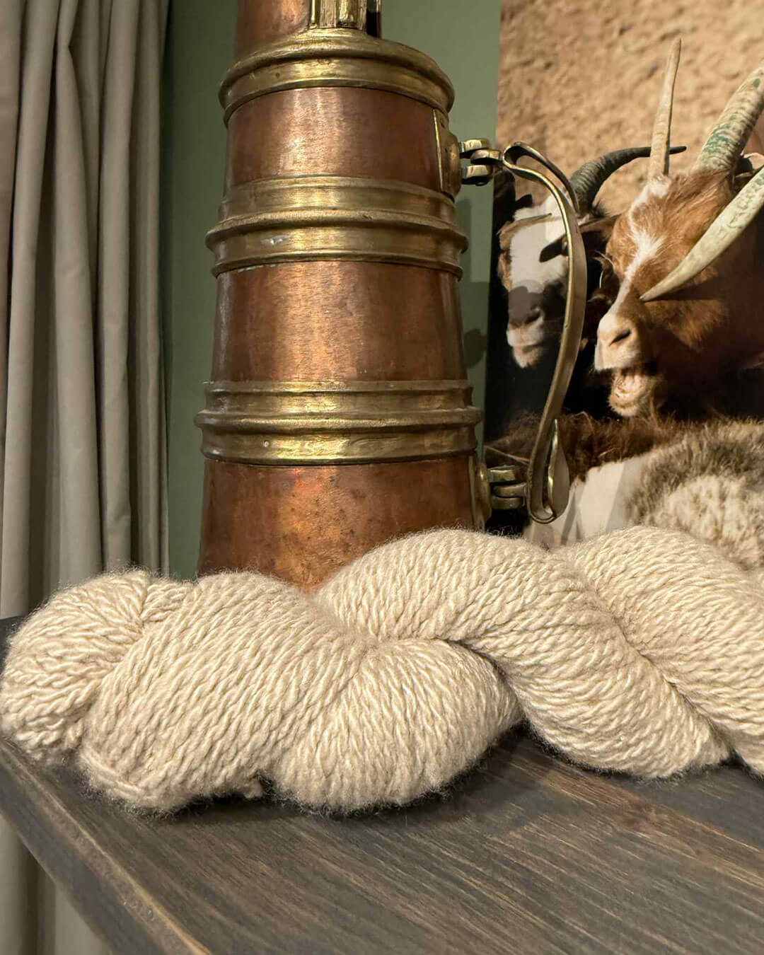 Håndspundet cashmeregarn i natural sand foran kobberkande.