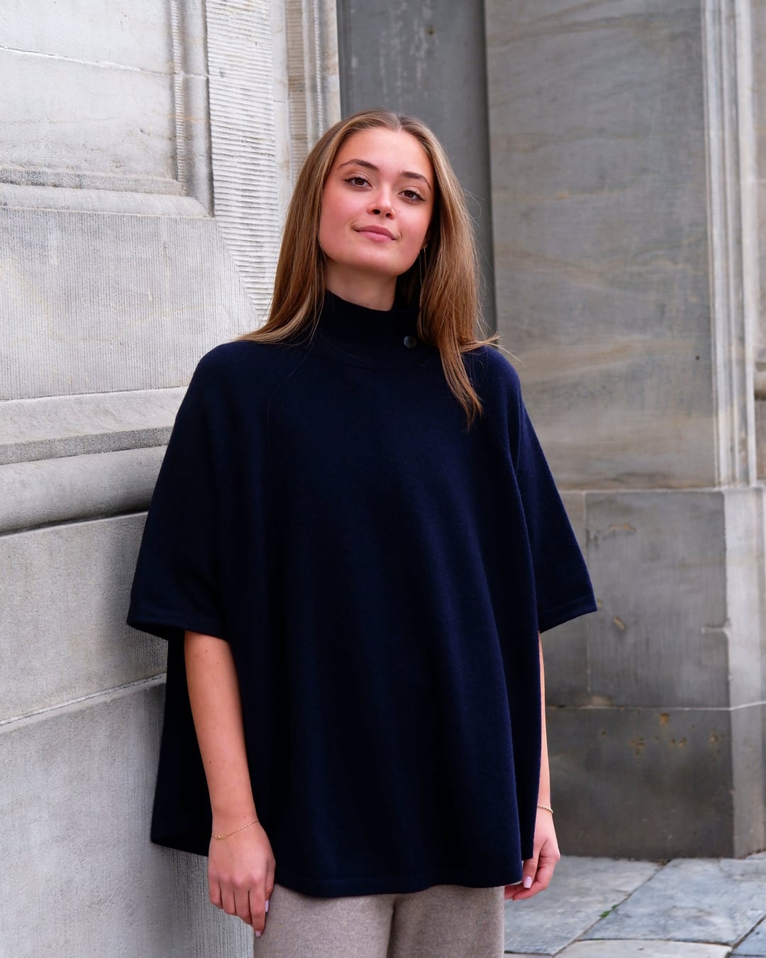Kvinde iført cashmere poncho Enkh i Dark navy med høj hals og knapper.