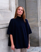 Kvinde iført cashmere poncho Enkh i Dark navy med høj hals og knapper.