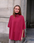 Kvinde iført cashmere poncho Enkh i Raspberry med høj hals og knapper.