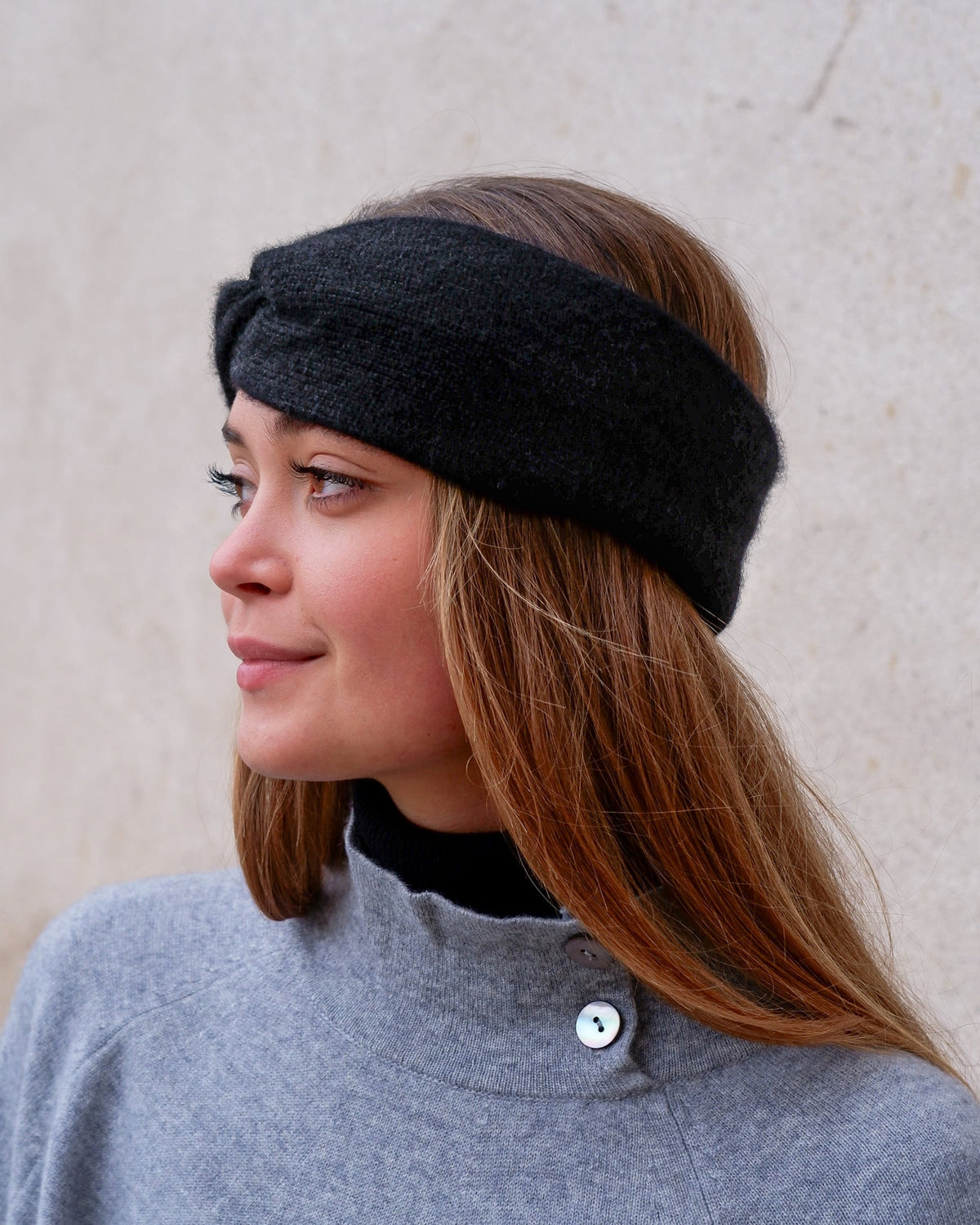 Model iført cashmere pandebånd i Black set fra siden.