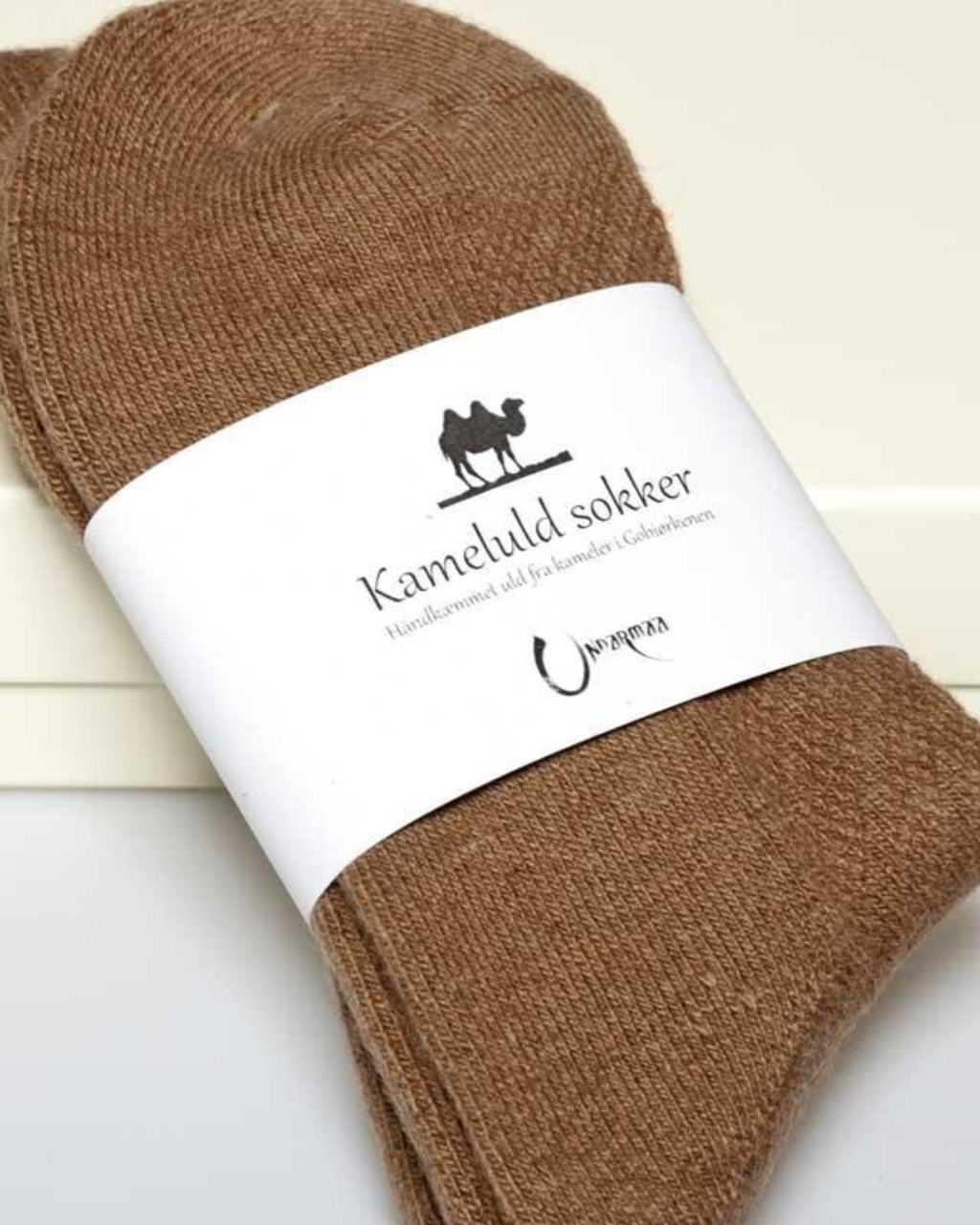 Detaljebillede af kameluldsokker med label, der viser materialet og kvaliteten.
