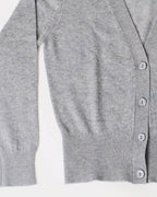 Nærbillede af cashmere cardigan i lys grå, der viser detaljerne i ribben ved håndleddet og taljen.