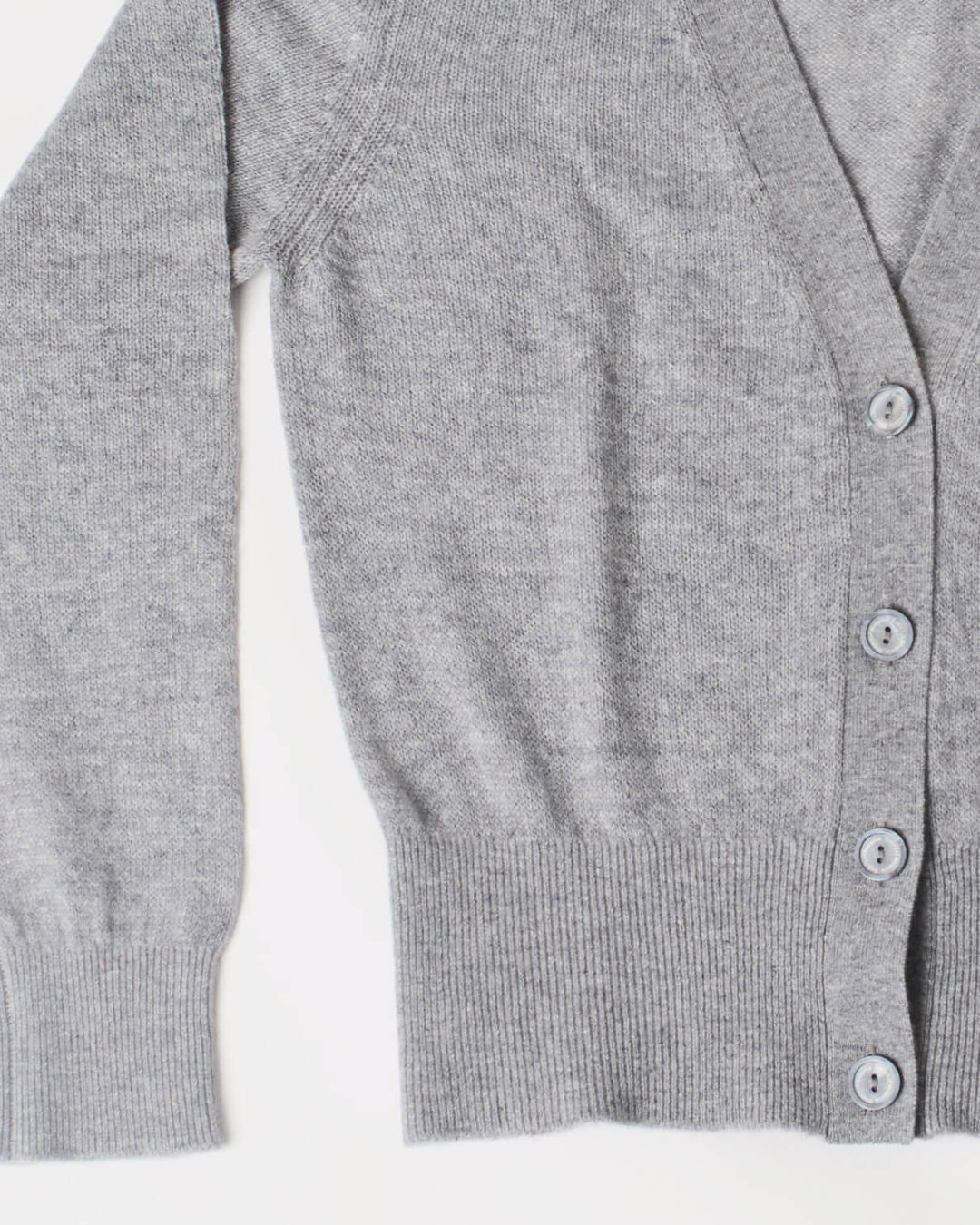 Nærbillede af cashmere cardigan i lys grå, der viser detaljerne i ribben ved håndleddet og taljen.