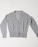 Helhedsbillede af lys grå cashmere cardigan med V-udskæring liggende fladt.