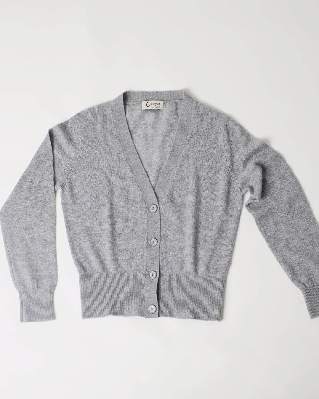 Helhedsbillede af lys grå cashmere cardigan med V-udskæring liggende fladt.