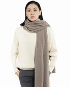 Model med det store naturfarvede cashmere tørklæde i mørk gråbeige svøbt om halsen.