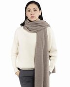 Model med det store naturfarvede cashmere tørklæde i mørk gråbeige svøbt om halsen.