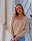 Kvinde iført cashmere bluse i Natural sand med flæsedetaljer ved halsudskæring.
