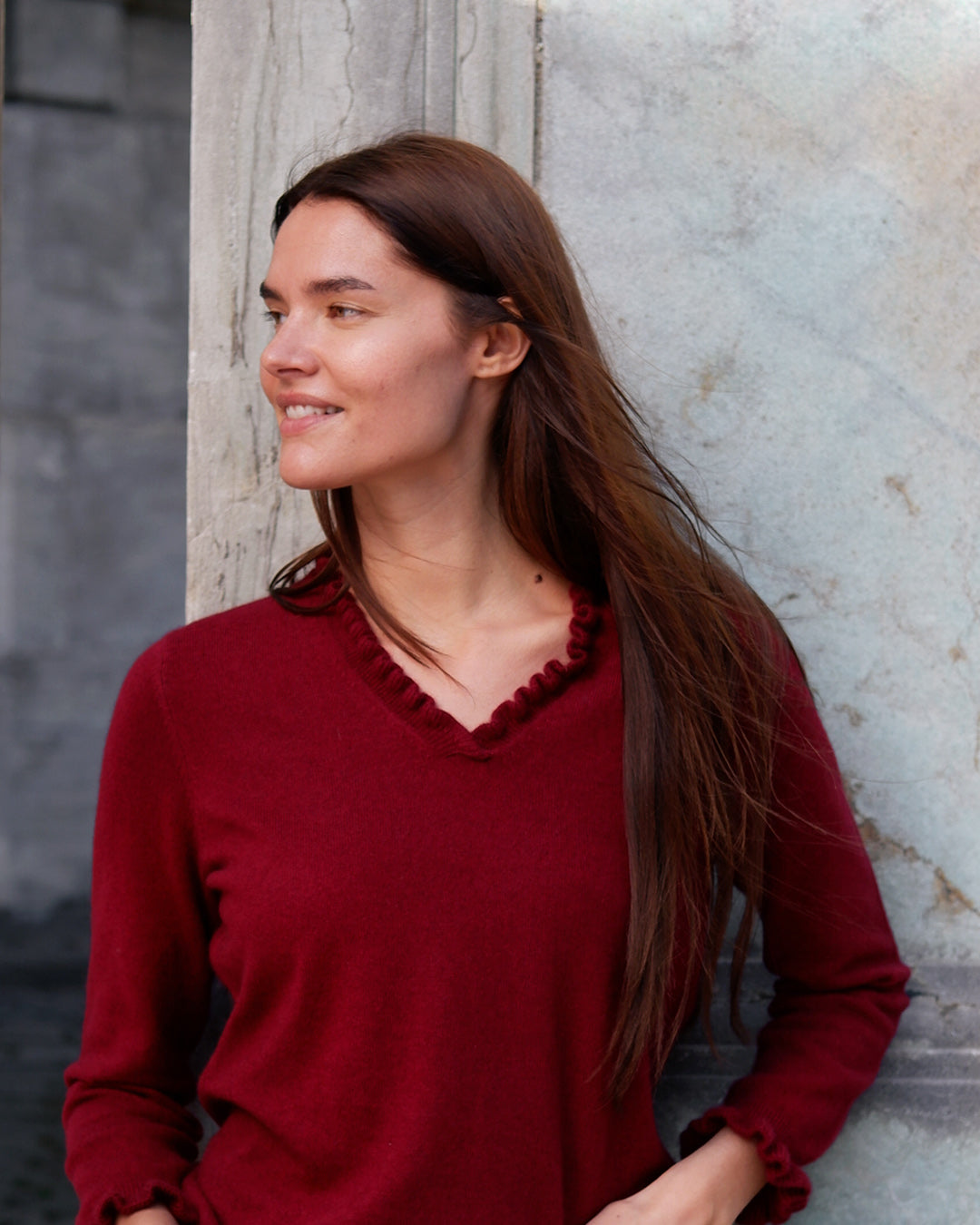 Kvinde iført cashmere bluse i Bordeaux med flæsedetaljer ved halsudskæring.
