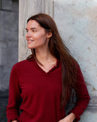Kvinde iført cashmere bluse i Bordeaux med flæsedetaljer ved halsudskæring.