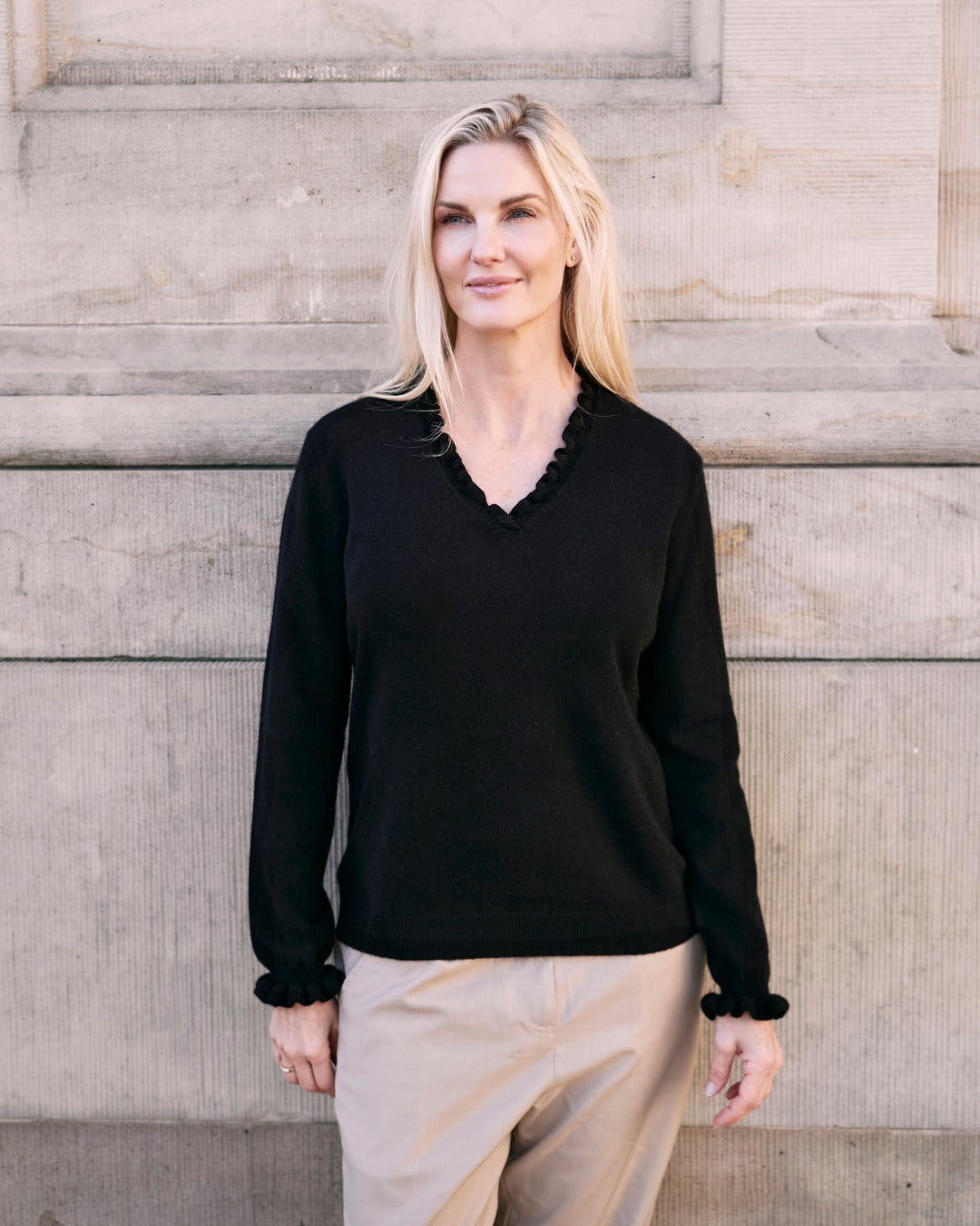 Kvinde iført cashmere bluse i Black med flæsedetaljer ved halsudskæring.