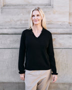 Kvinde iført cashmere bluse i Black med flæsedetaljer ved halsudskæring.