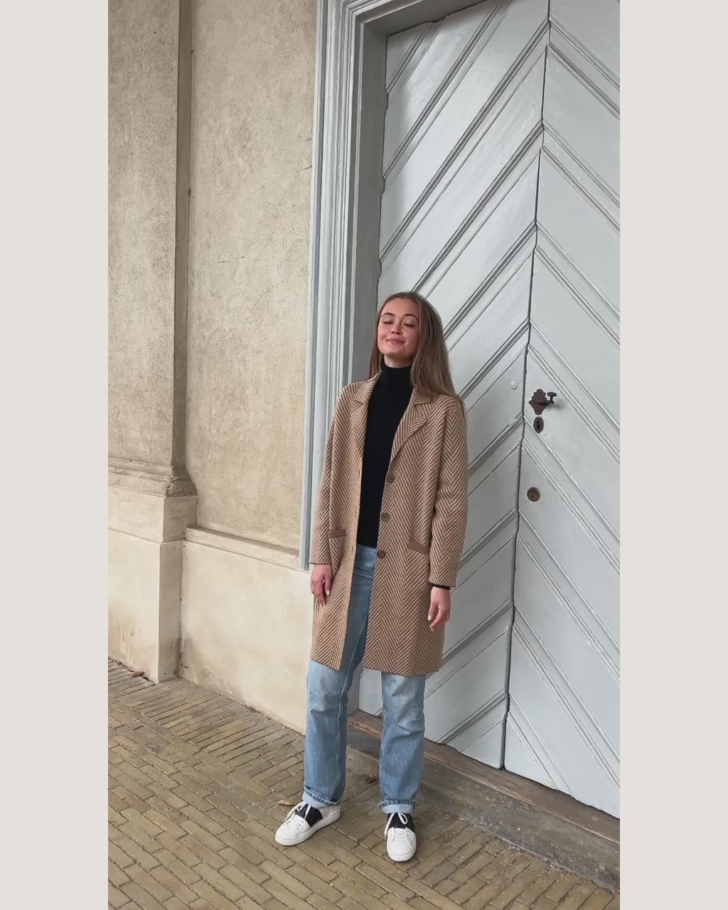 Video af model i kameluldsfrakken Khongor udendørs, samt nærbillede af sildebensmønsteret.