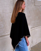 Sort cashmere poncho Sarnai set bagfra, med taupefarvet kontrastkant.