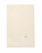 Det store naturfarvede cashmere tørklæde i lys beige ligger fladt.
