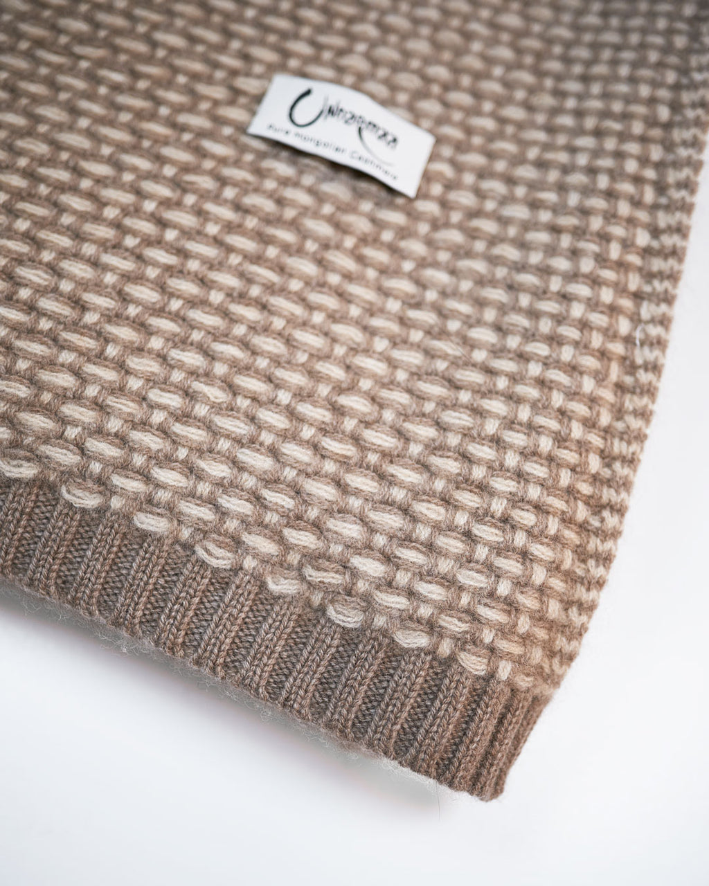 Kantdetalje på Taiga cashmere plaid med ribstrikket afslutning og Undarmaa-label.