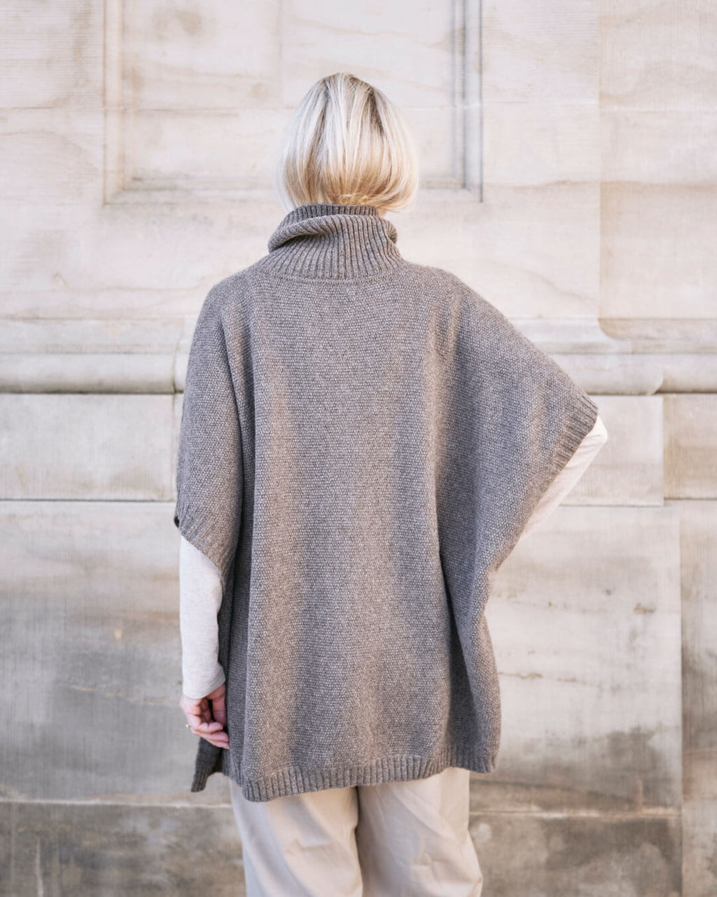 Model bære Tara yakuld poncho med rullekrave i Yak Dark Grey set bagfra.