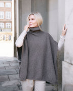 Model ved portal iført Tara yakuld poncho med rullekrave.