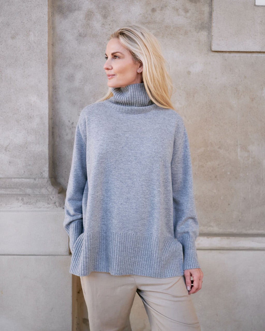 Model iført klassisk cashmere sweater med sadelskuldre og løs pasform i soft grey