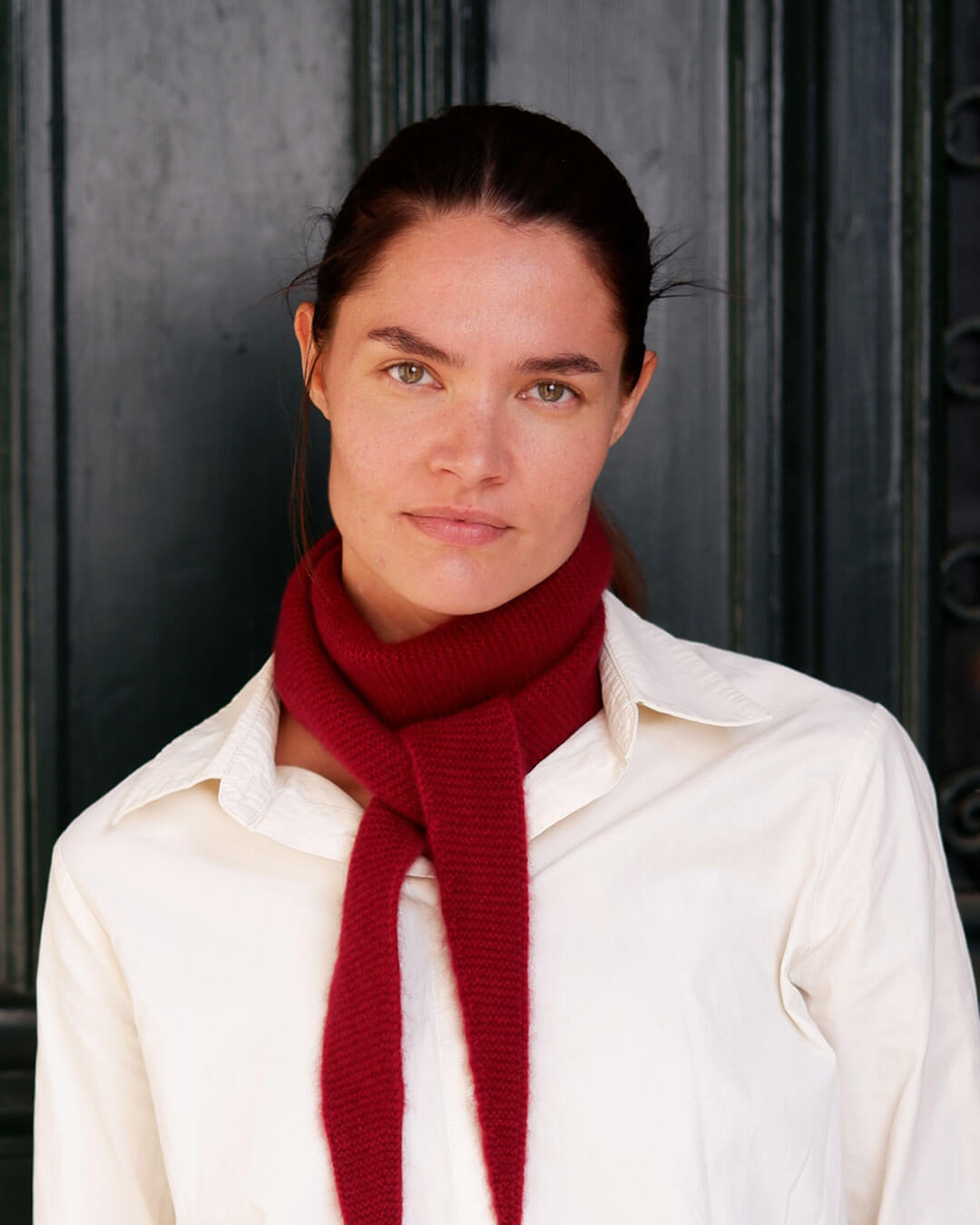 Model med Taiga cashmere trekanttørklæde i Bordeaux over lys skjorte.