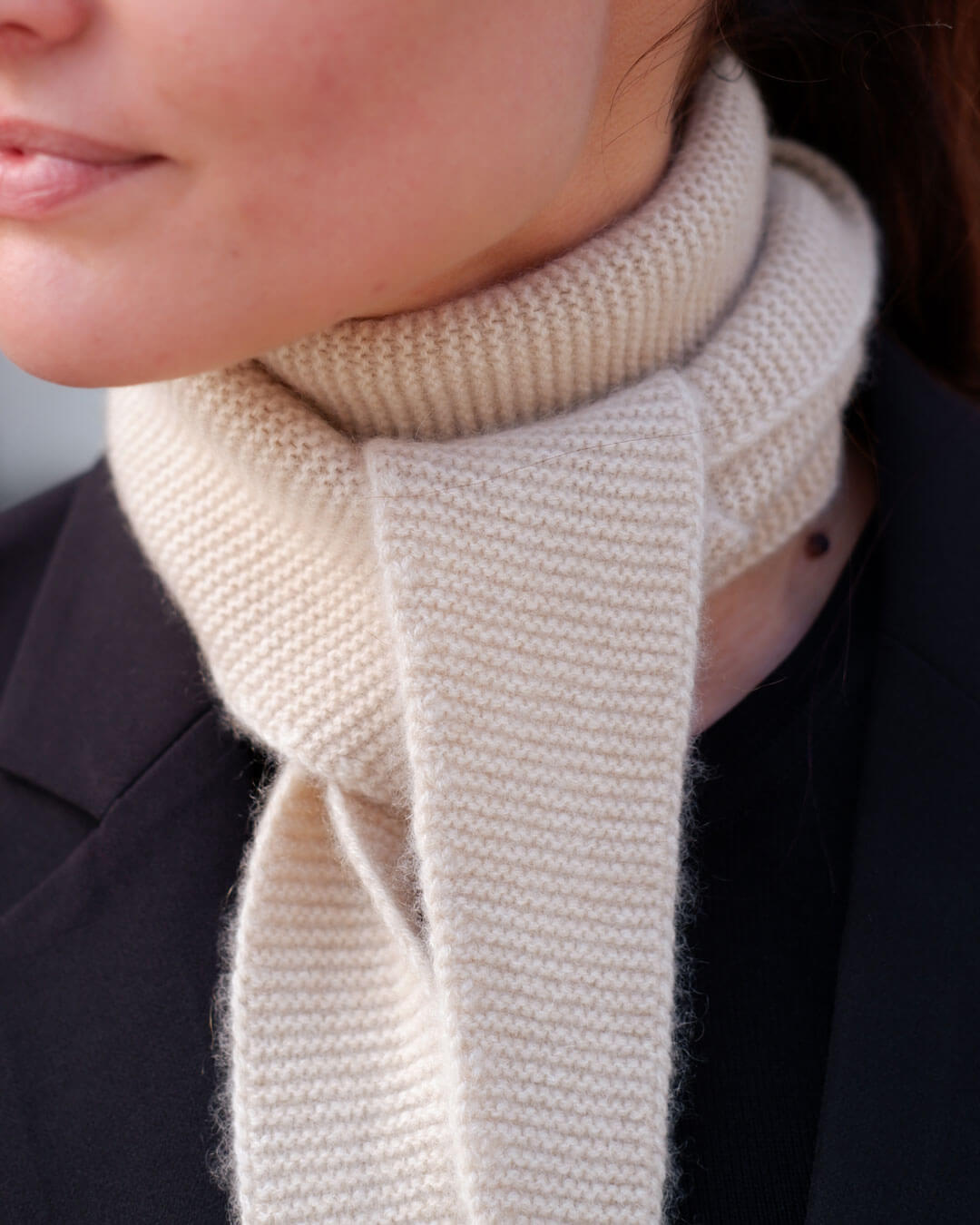 Taiga cashmere trekanttørklæde i Natural Sand – close-up af rillestrik ved halsen.
