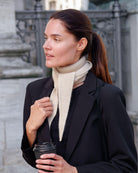 Model med Taiga cashmere trekanttørklæde i Natural Sand under sort blazer.