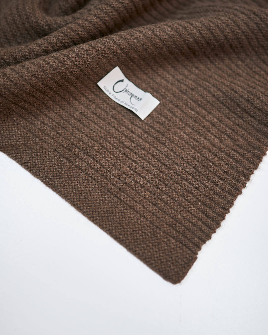 Strikket plaid i 100% yakuld i farven Yak Mocha med Undarmaa logo.