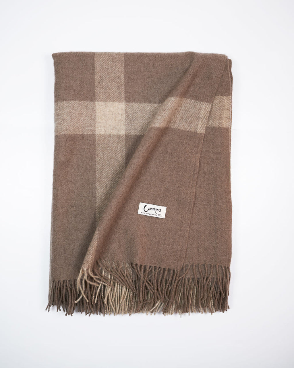 Vævet plaid i 100% yakuld med naturlige tern i beige og brun let foldet.