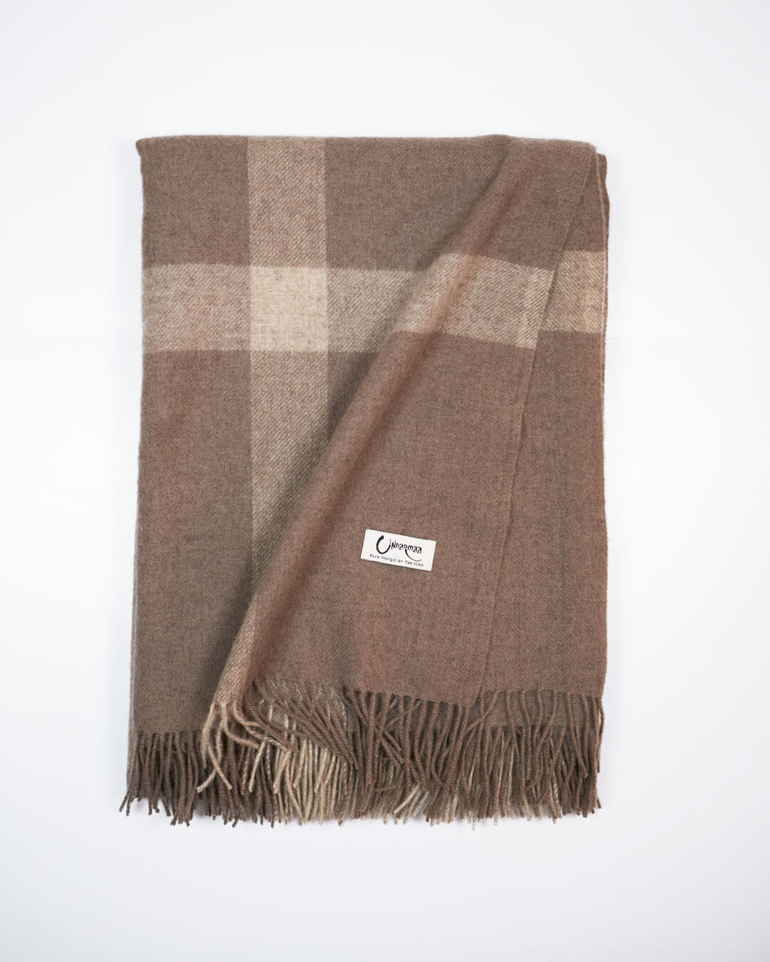 Vævet plaid i 100% yakuld med naturlige tern i beige og brun let foldet.