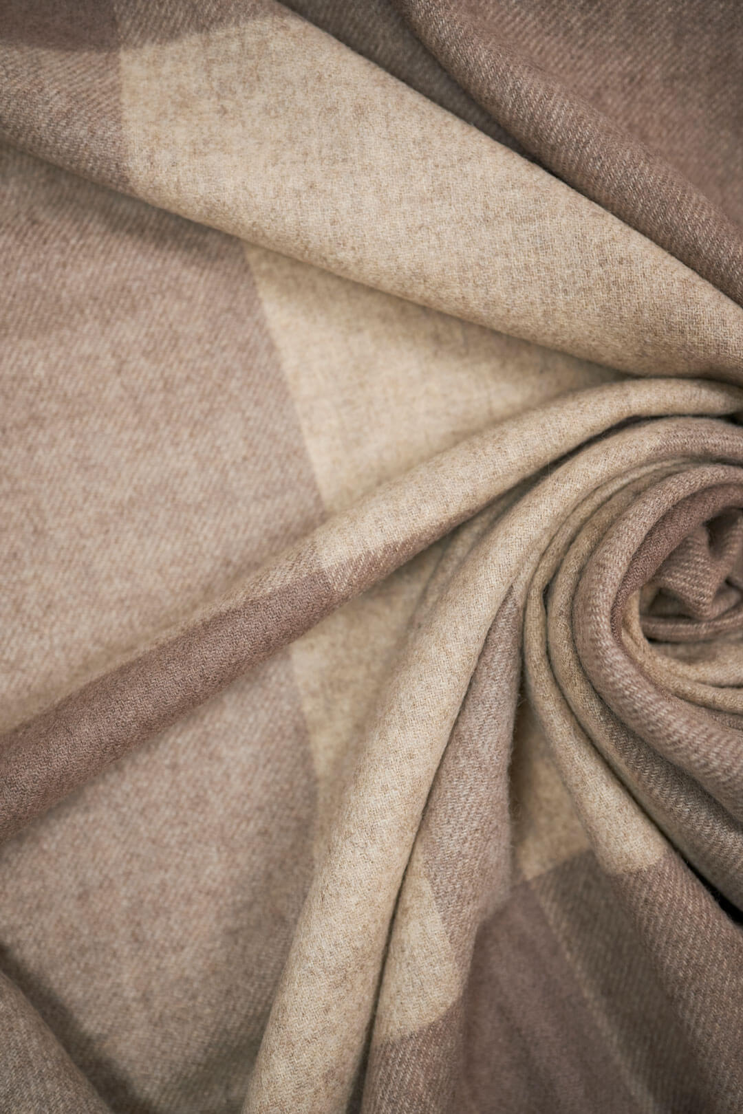 Vævet plaid i 100% yakuld med naturlige tern i beige og brun rullet så man fornemmer strukturen.